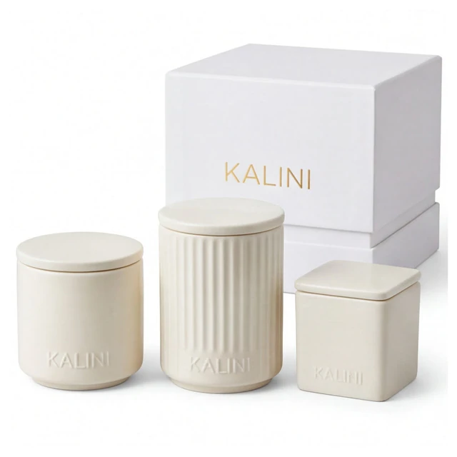 Ivory smooth, fluted and square ceramic candle jars with lids beside stacked boxes