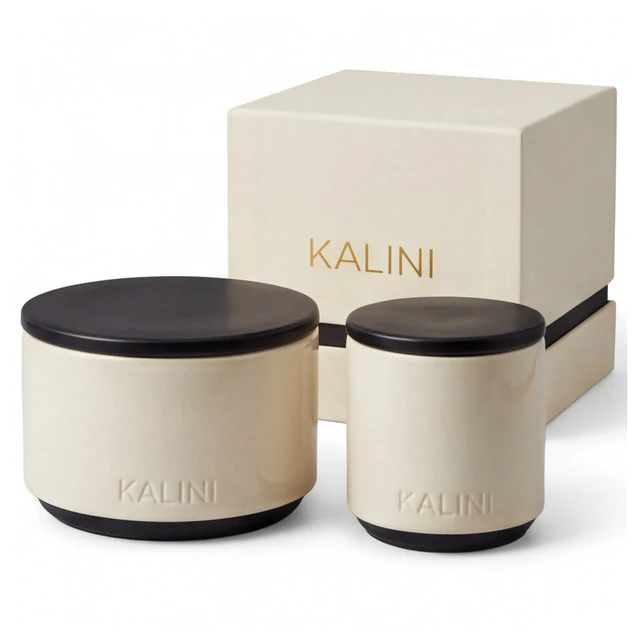 Ivory ceramic candle jars with dark top and base accents beside a pale box