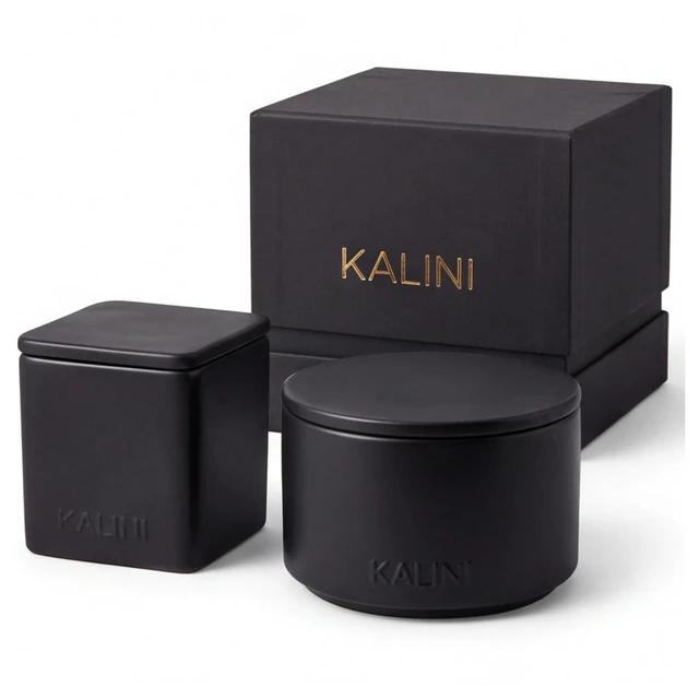 Black square and round ceramic candle vessels with flat lids and stacked boxes