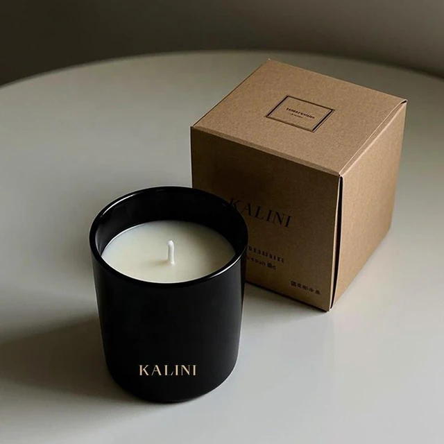 Black round glass candle jar beside a kraft-colored KALINI box