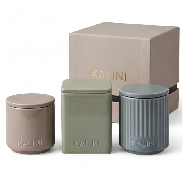 Pink round, green square and blue fluted ceramic jars beside a pale box
