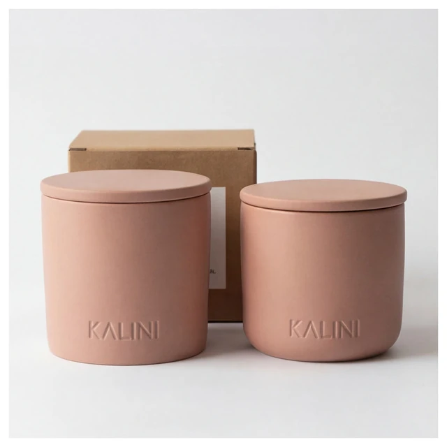 Two pink round ceramic candle jars with flat lids and a kraft-colored box