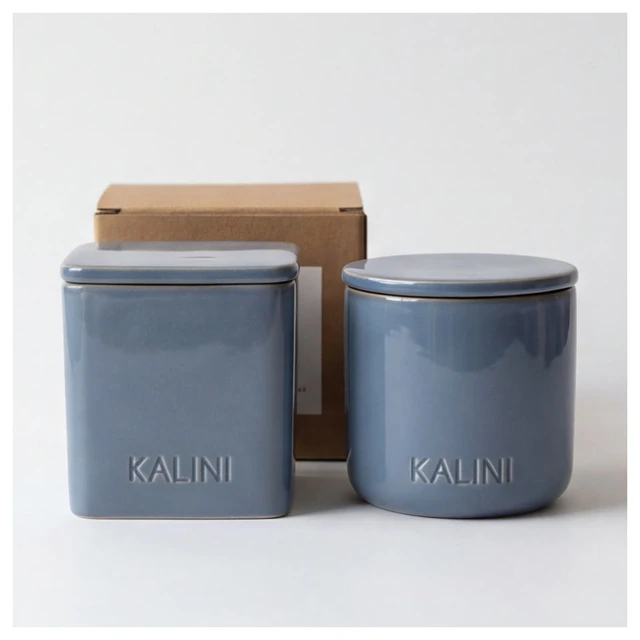 Blue square and round ceramic candle jars with flat lids and a kraft-colored box
