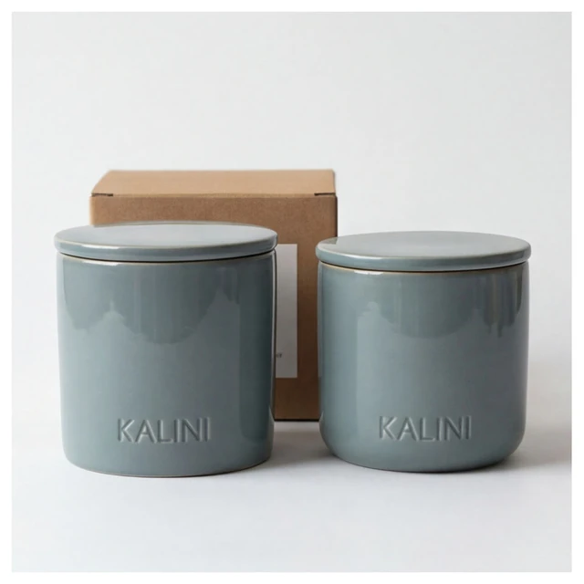 Green-gray round ceramic candle jars with flat lids and a kraft-colored box