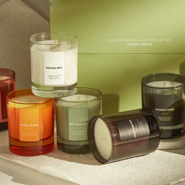 Colored round glass candle jars with front labels and one jar lying on its side