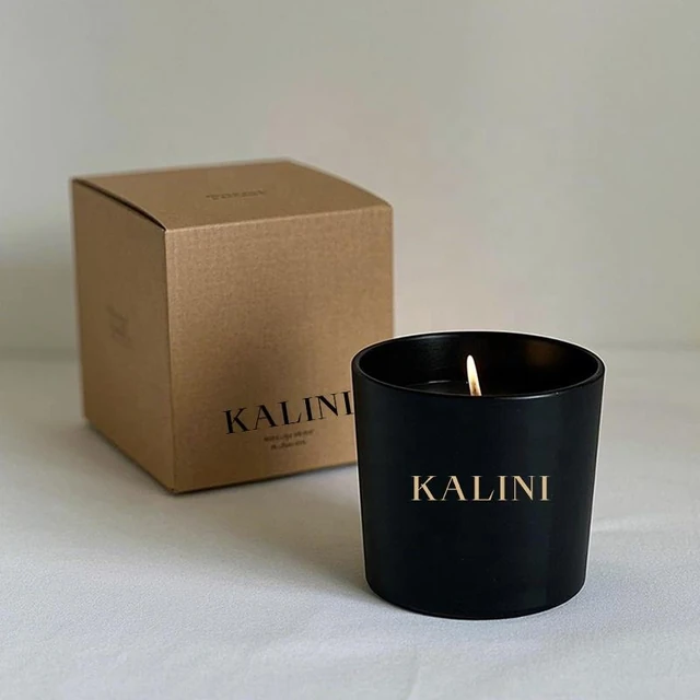Wide black glass candle jar with gold-colored lettering and a box